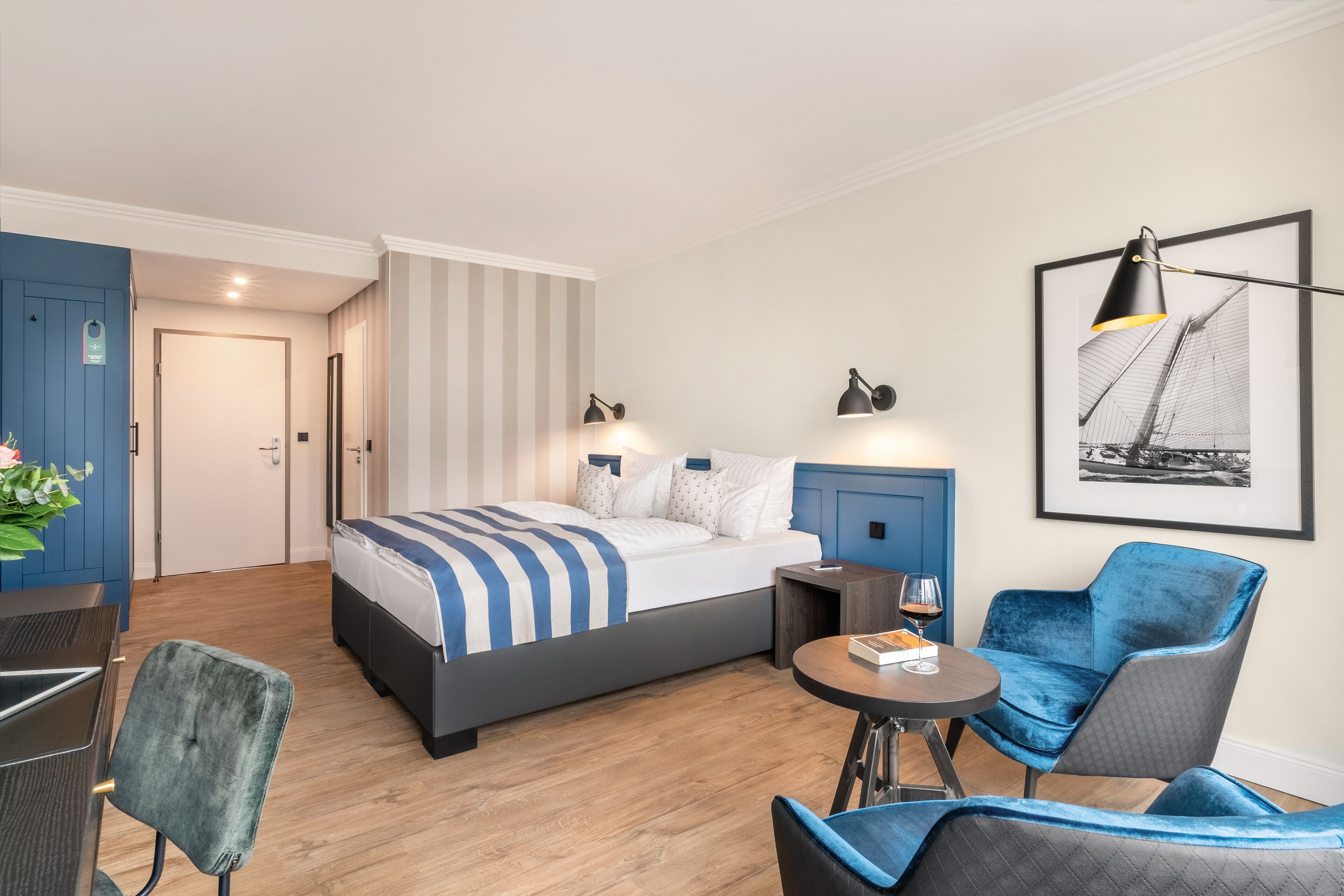 Une chambre d’hôtel avec un lit, un bureau, une chaise, une petite table et un tableau encadré au mur.