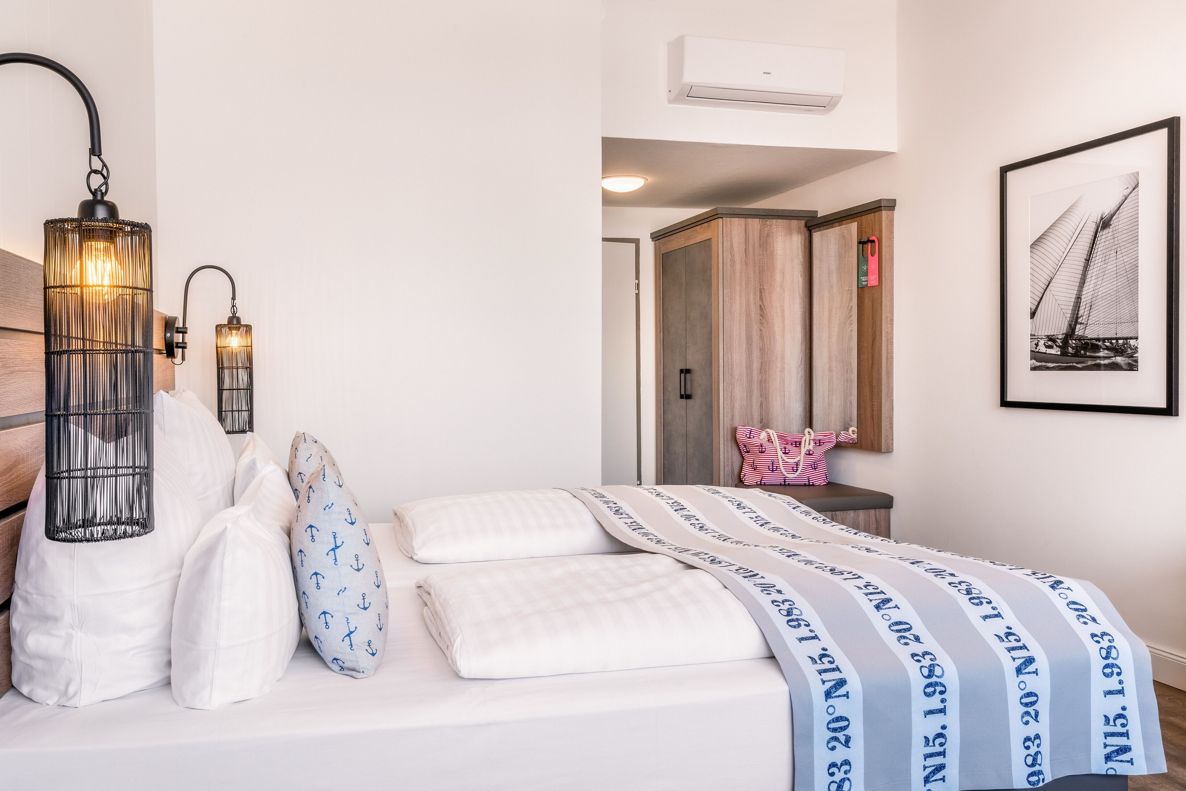A neatly made bed with a striped blanket, a bedside lamp, and a framed picture on the wall.