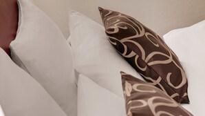 A bed with white and patterned pillows, a wooden headboard, and a wall-mounted light fixture. - Best Western Hotel Darmstadt Mitte (Darmstadt)