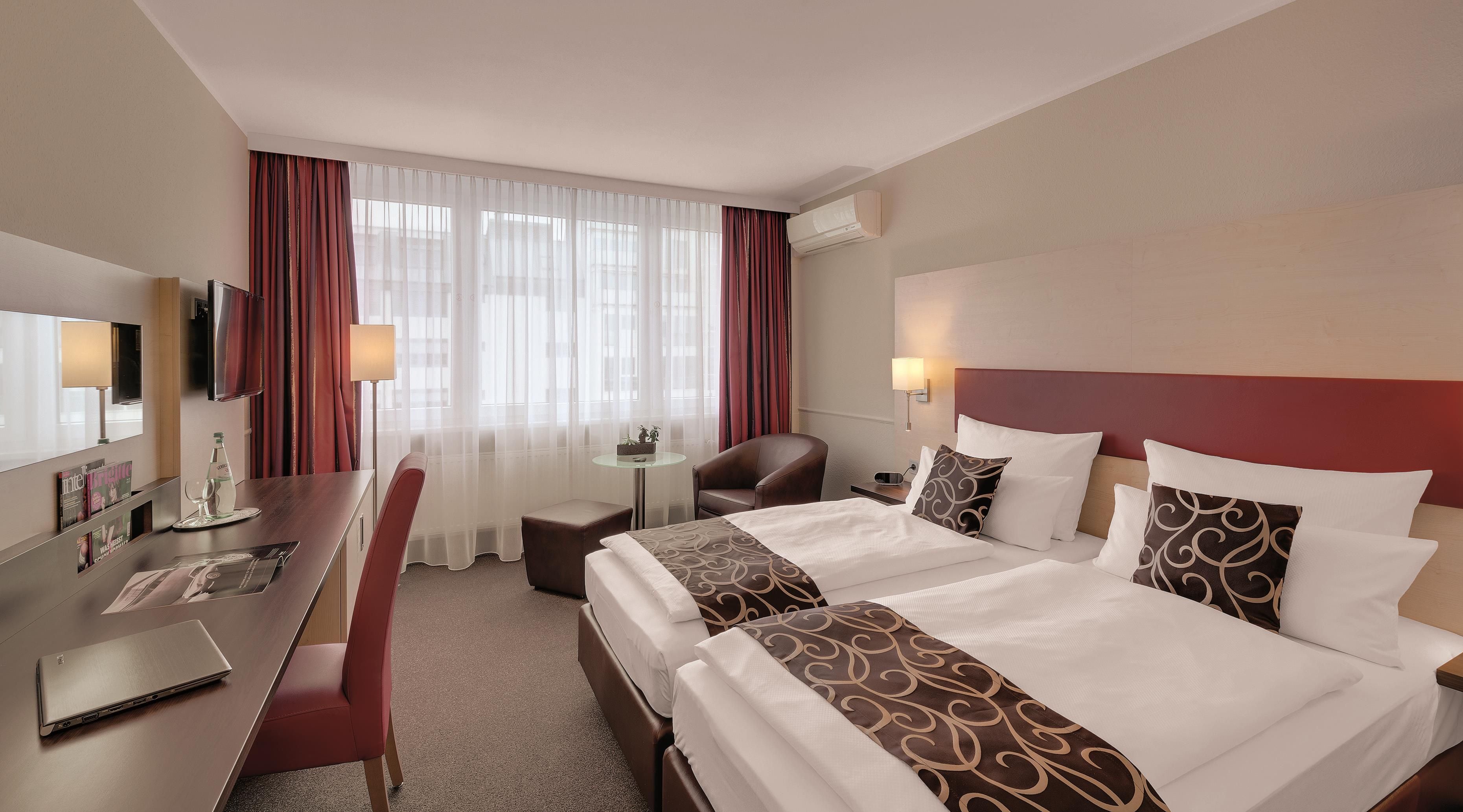 A hotel room with a bed, desk, chair, and a television.
