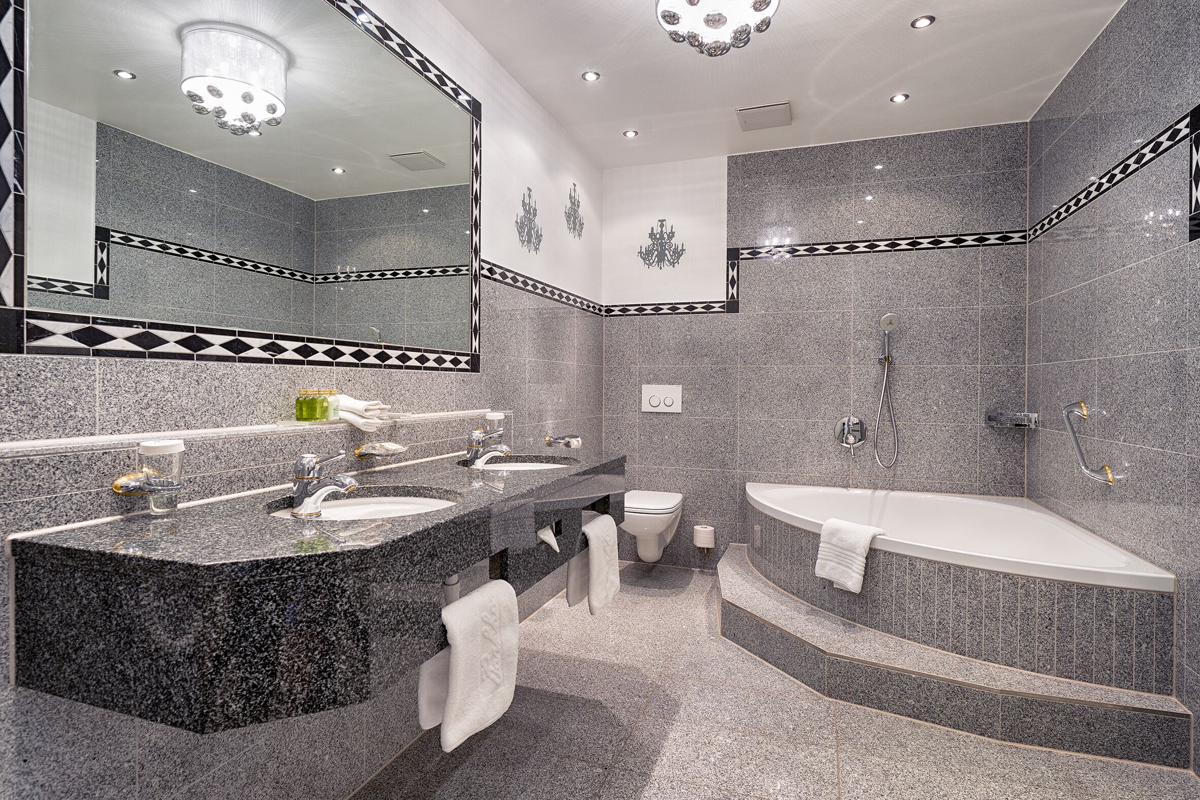 Un baño moderno con lavamanos de granito, zona de ducha separada y bañera independiente.