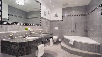 Un baño moderno con lavamanos de granito, zona de ducha separada y bañera independiente.