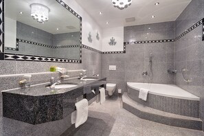 Ein modernes Badezimmer mit Marmorwaschtisch, separater Duschkabine und freistehender Badewanne.
