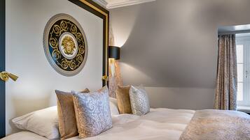 Une chambre d’hôtel avec un grand lit, des œuvres d’art décoratives au mur, une lampe et des rideaux à motifs.