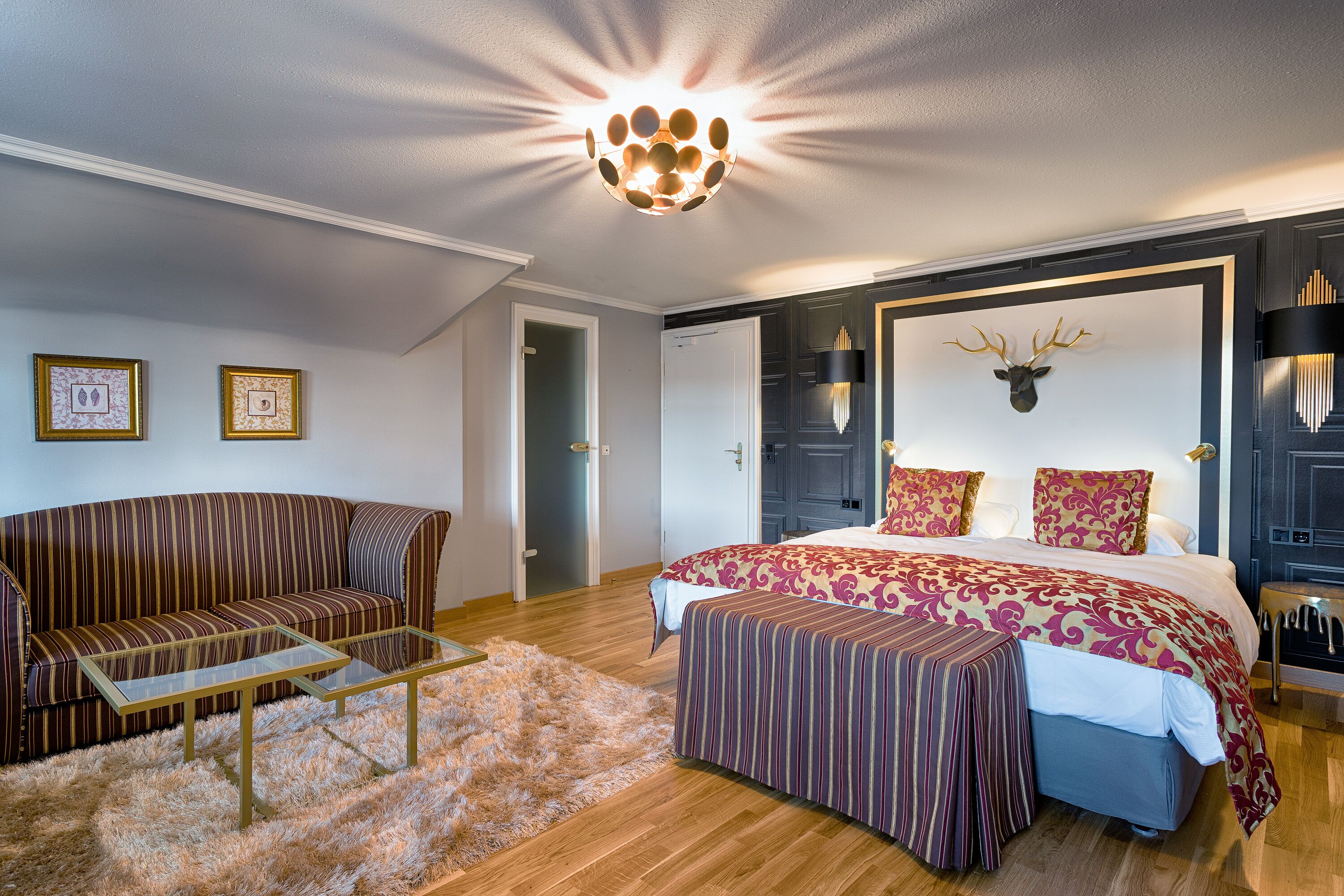 Une chambre avec un grand lit, un canapé, une table basse en verre et un tapis moelleux.
