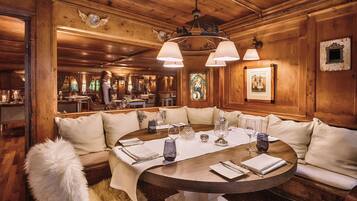 A cozy, wood-paneled dining area with a round table set for a meal, surrounded by cushioned seating.