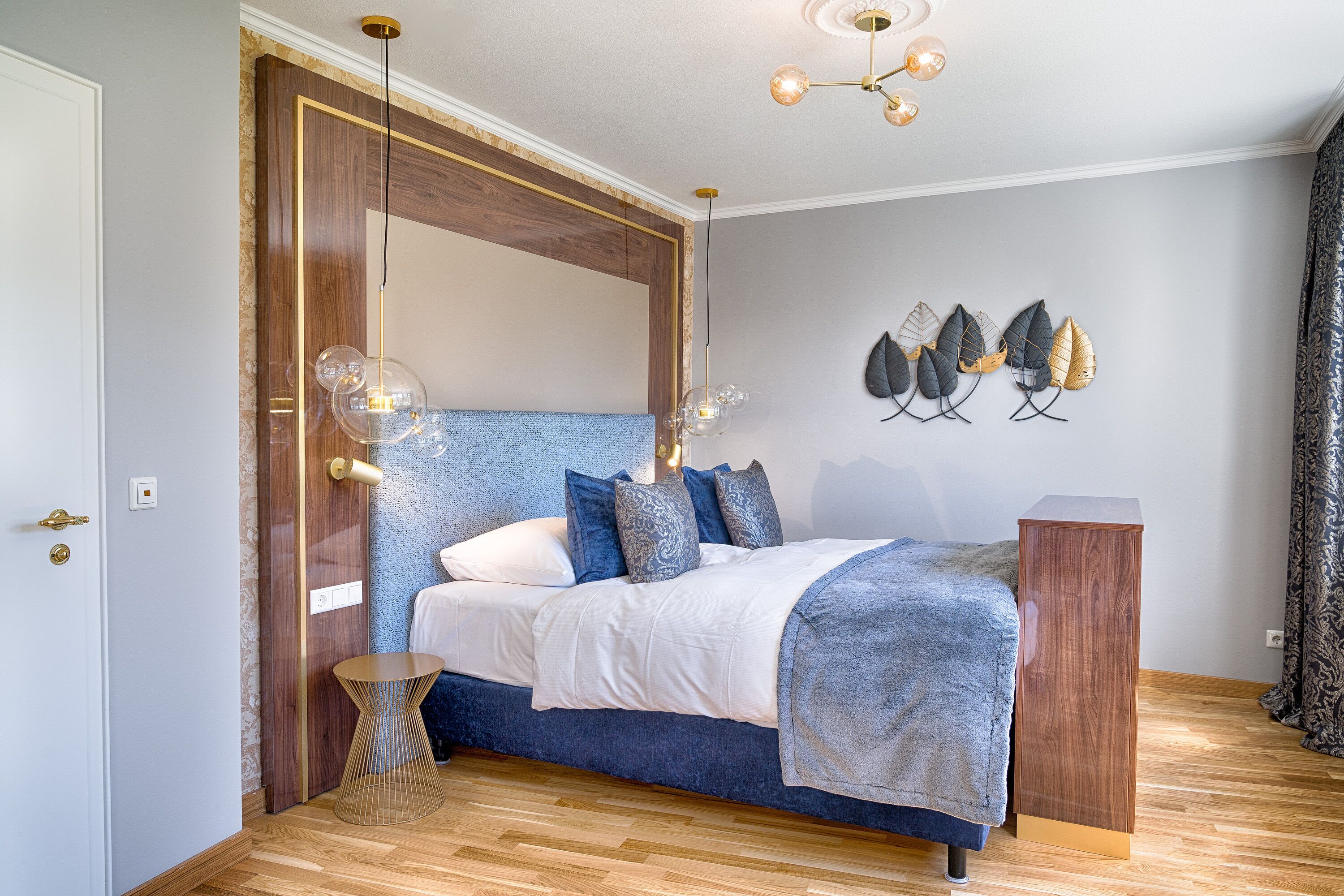A bedroom with a bed, a wooden headboard, a bedside table, and a wall-mounted light fixture.