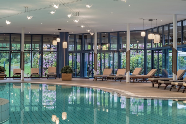 A swimming pool with lounge chairs and large windows.