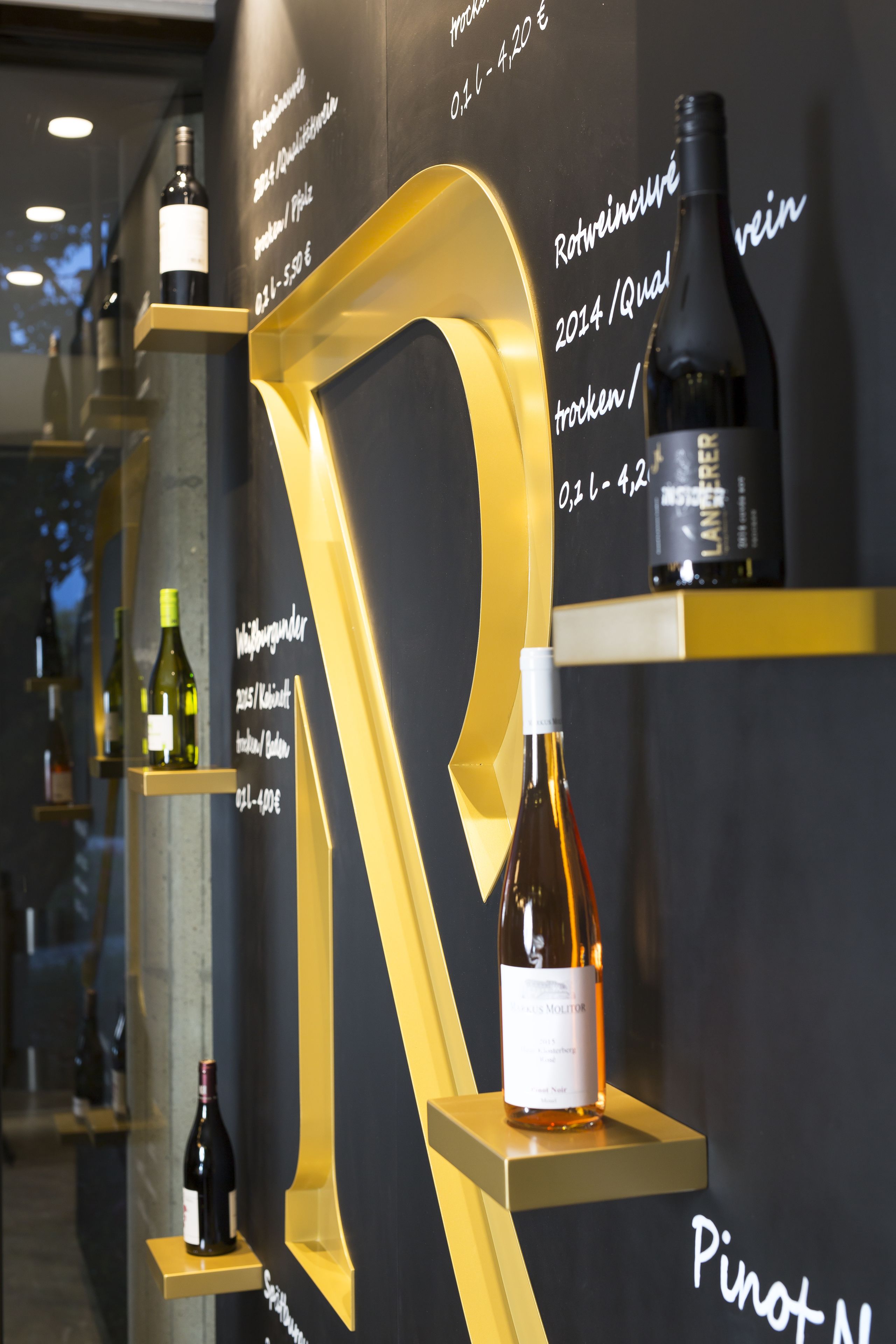 A wine display with bottles labeled with years and types, such as Pinot Noir and 2014/Qual.