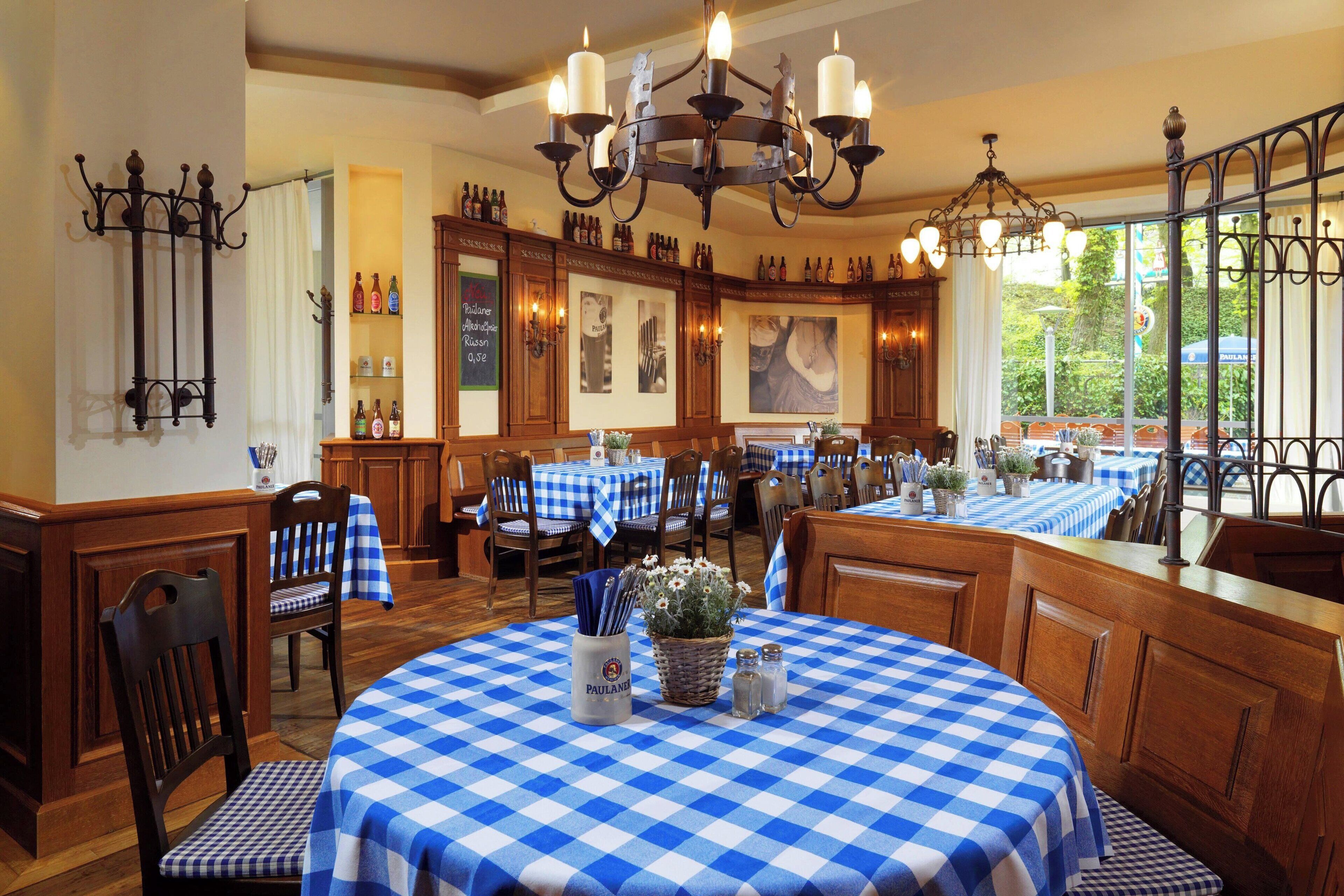 A restaurant with checkered tablecloths, wooden furniture, and a chandelier.