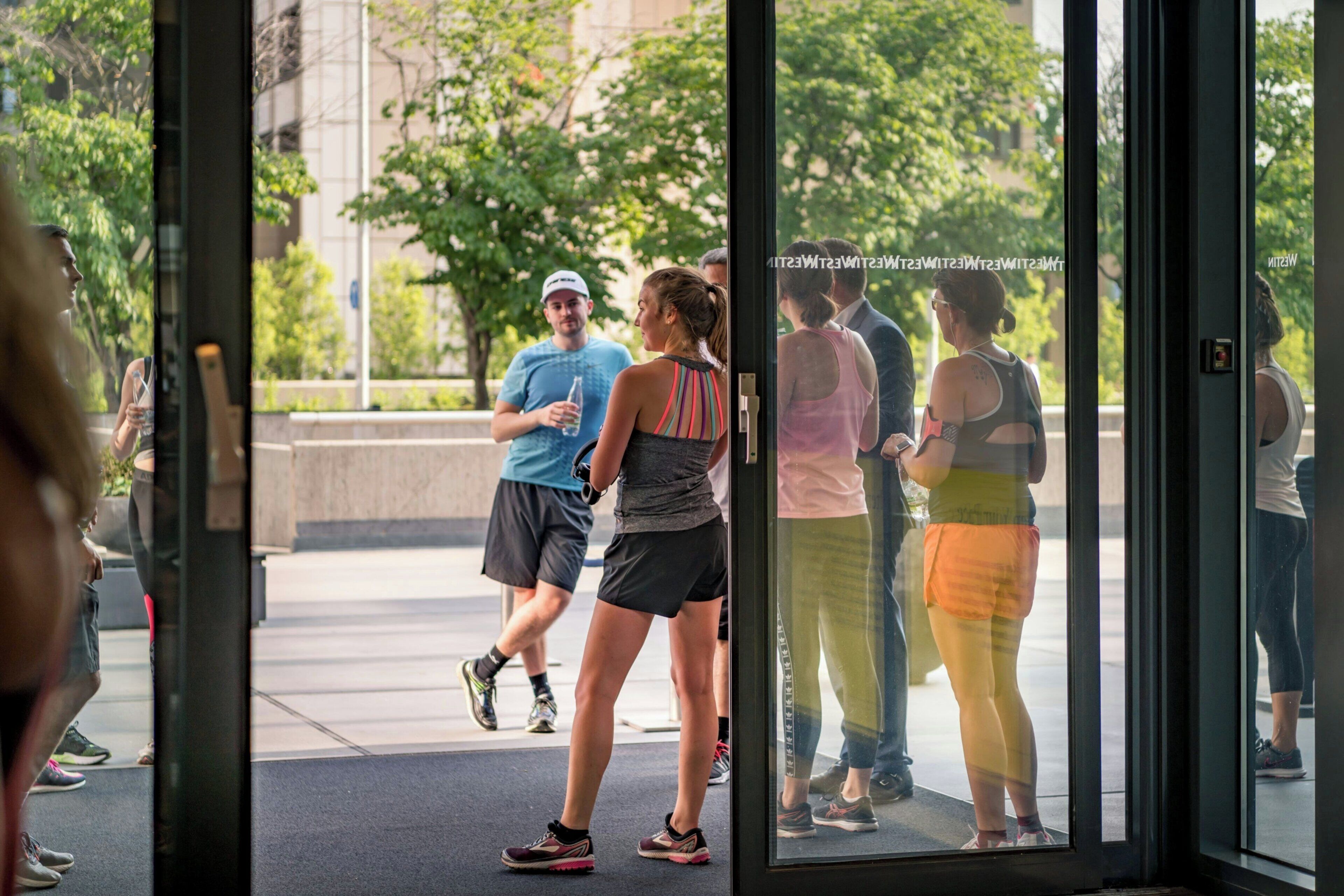 A group of people entering a building through a glass door.