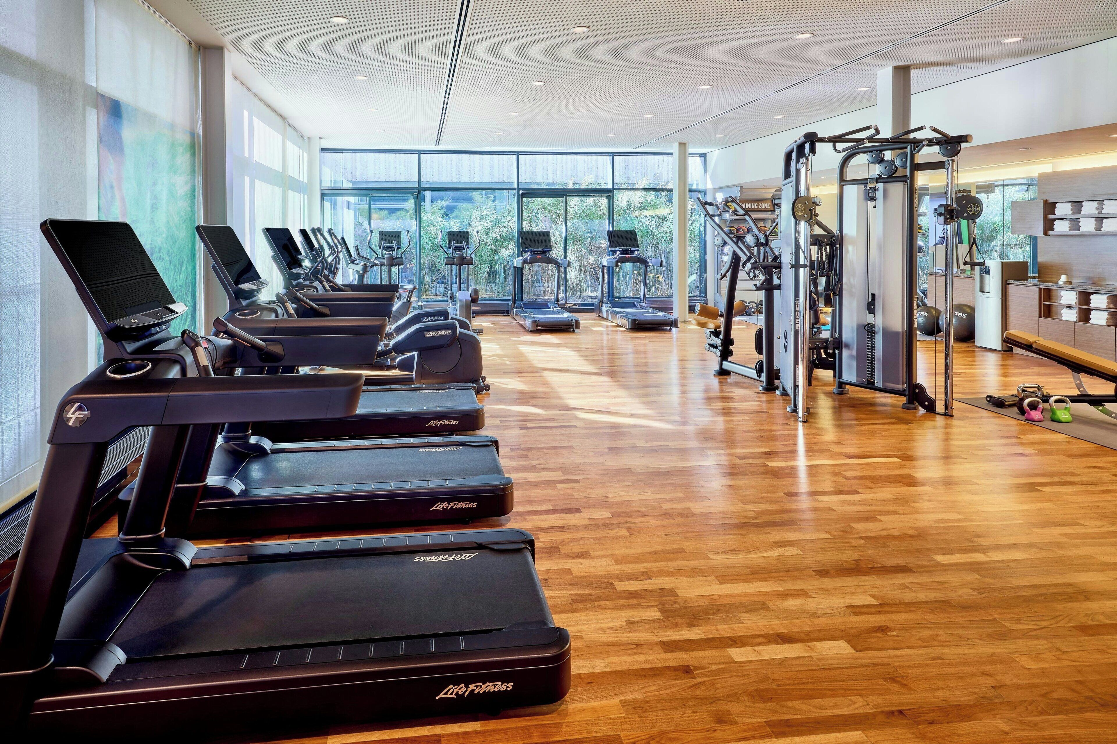 Un gimnasio con cintas de correr, elípticas y equipo de levantamiento de pesas.