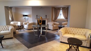 Un salon spacieux doté d’une cheminée, de nombreux sièges, notamment un canapé et des fauteuils, et d’une table basse en verre.