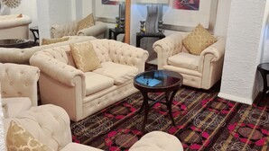 Un salon avec un grand miroir, deux canapés, une table basse et un tapis à motifs.
