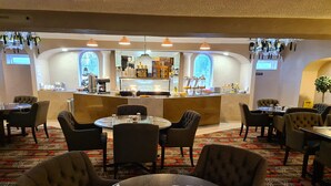 Un restaurant avec des tables et des chaises rondes, un coin bar et une vue sur la cuisine.