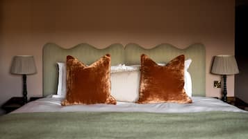A neatly made bed with two large pillows, a green headboard, and two bedside lamps.