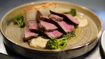 A plate of sliced meat, mashed potatoes, and broccoli.
