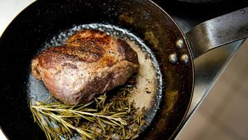 A pan with a seared steak and rosemary.