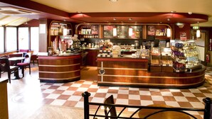 Een restaurant met een schaakbordvloer, een houten toonbank en verschillende soorten eten.