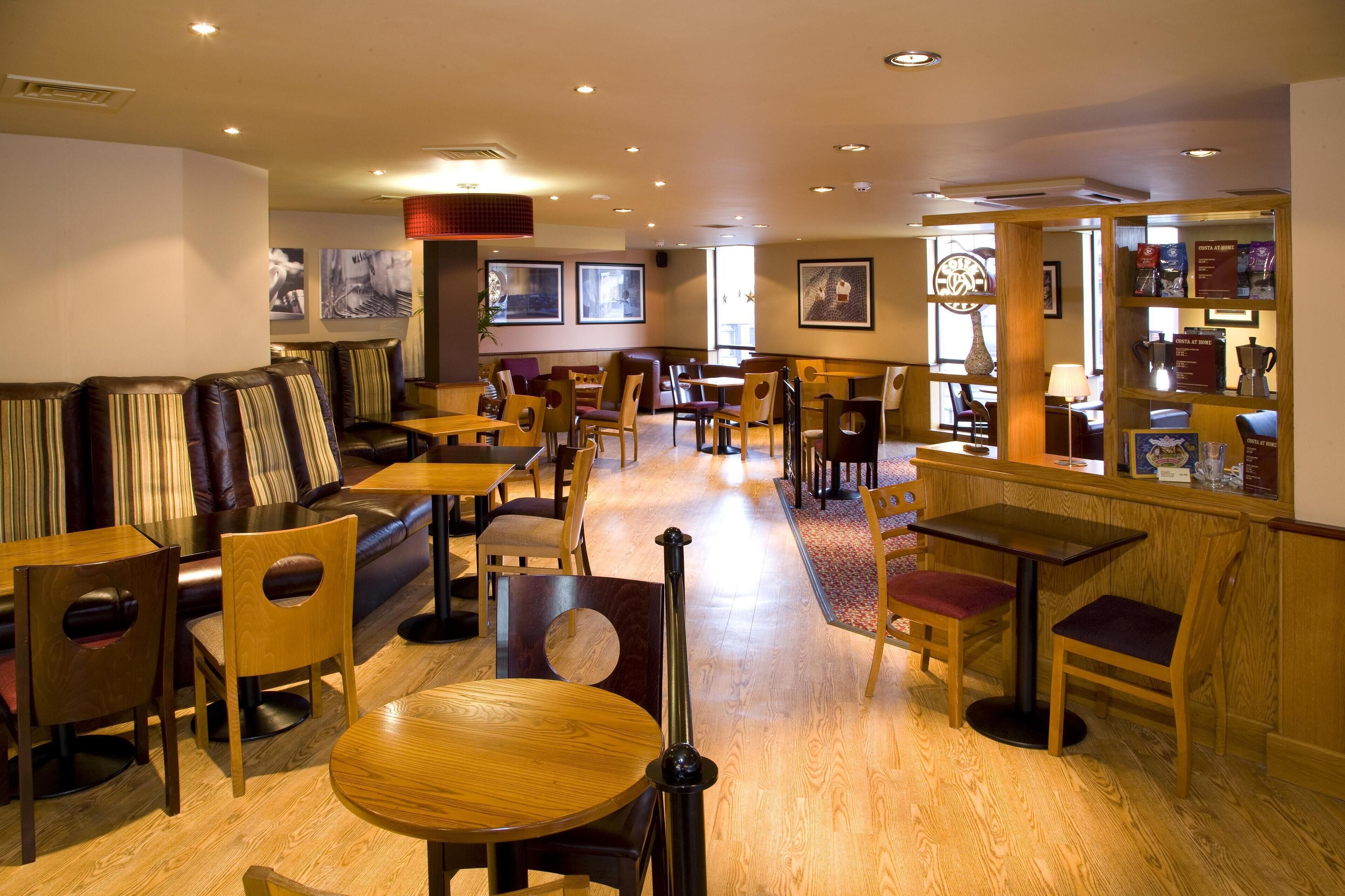 A restaurant with wooden tables and chairs, a bar area, and framed artwork on the walls.