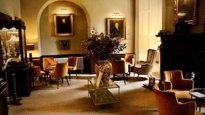A cozy lounge area with a fireplace, comfortable seating, and a vase with flowers. - Lumley Castle Hotel (Chester-le-Street)