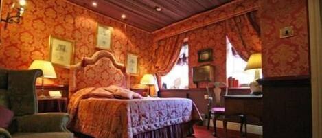 A hotel room with a large bed, two bedside tables with lamps, a chair, and a desk.