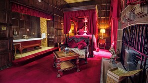 A room with a large bed, a wooden vanity with a mirror, a red carpet, and a red curtain. - Lumley Castle Hotel (Chester-le-Street)