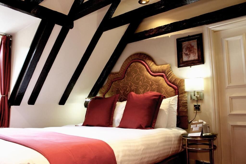 A hotel room with a bed, a nightstand, a lamp, and a framed picture on the wall.