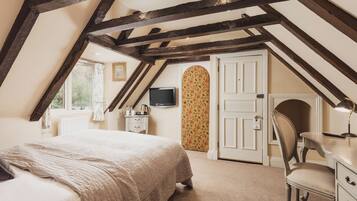 Ein Schlafzimmer mit einem großen Bett, einem Schreibtisch, einem Sessel, einem Fernseher und einem Kleiderschrank.