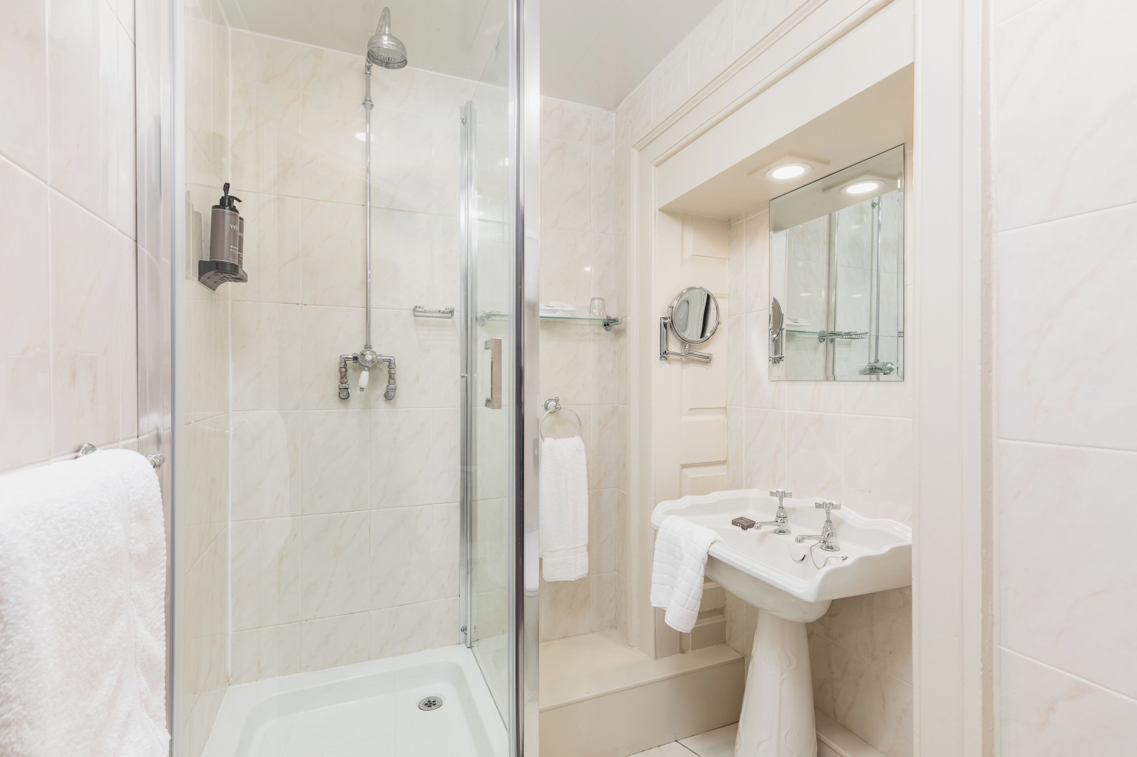 Une salle de bain moderne avec une douche à parois de verre, un lavabo blanc et un miroir.