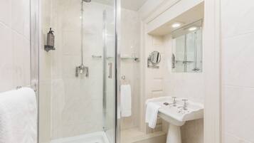 Une salle de bain moderne avec une douche à parois de verre, un lavabo blanc et un miroir.