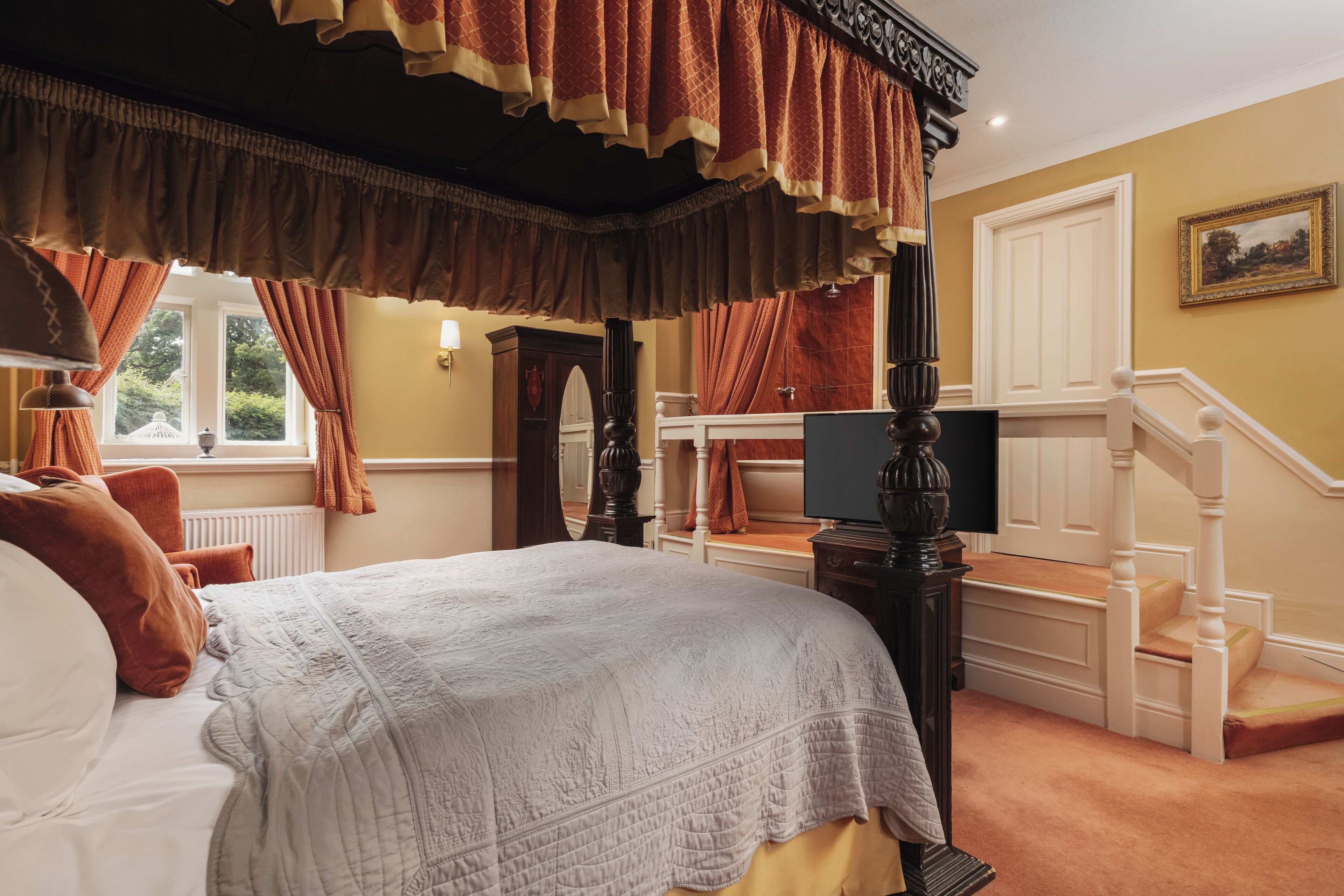 Una camera da letto con un letto a baldacchino, una scala e una finestra con tende.
