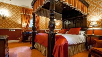 A four-poster bed with a canopy, a wooden nightstand, and a lamp on the right side.