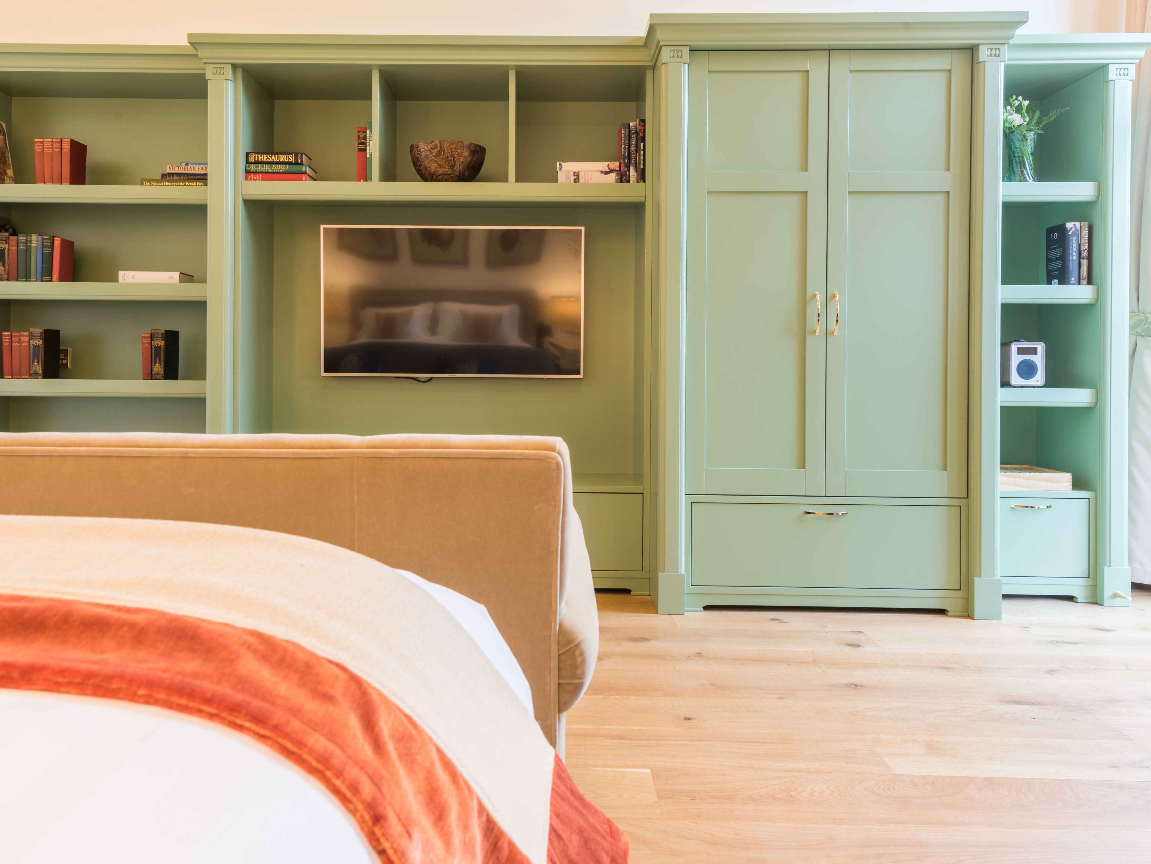 A bedroom with a bed, a television, and a green wardrobe.