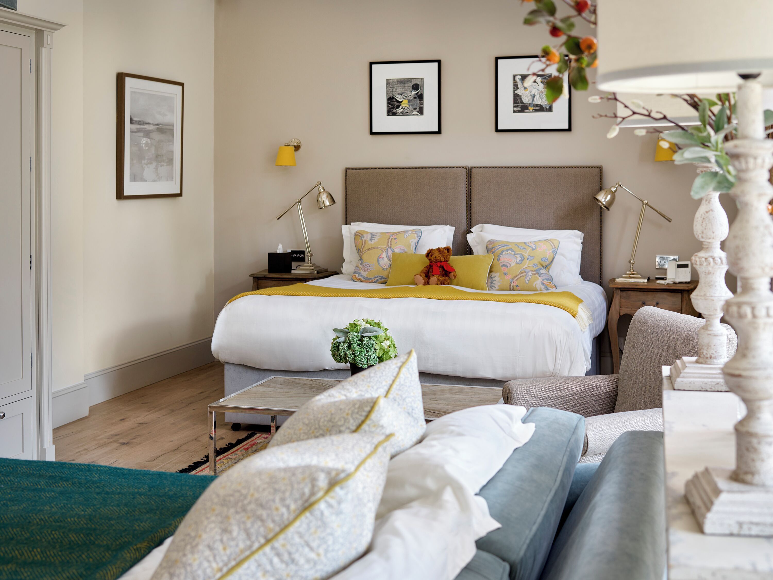 Une chambre bien rangée, avec un grand lit, des tables de chevet, une petite table et une chaise.