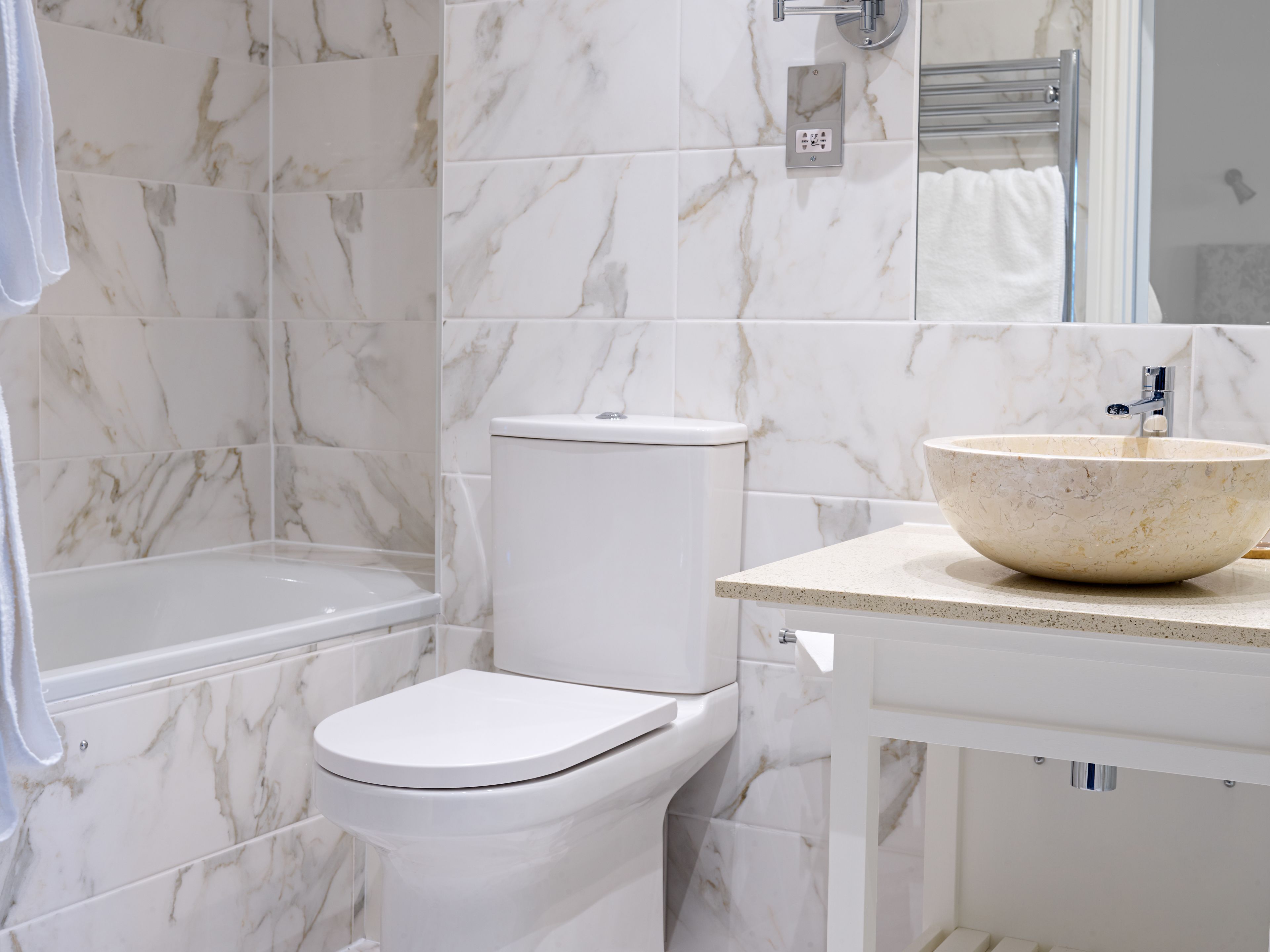 A bathroom with a toilet, a sink with a marble basin, and a bathtub.