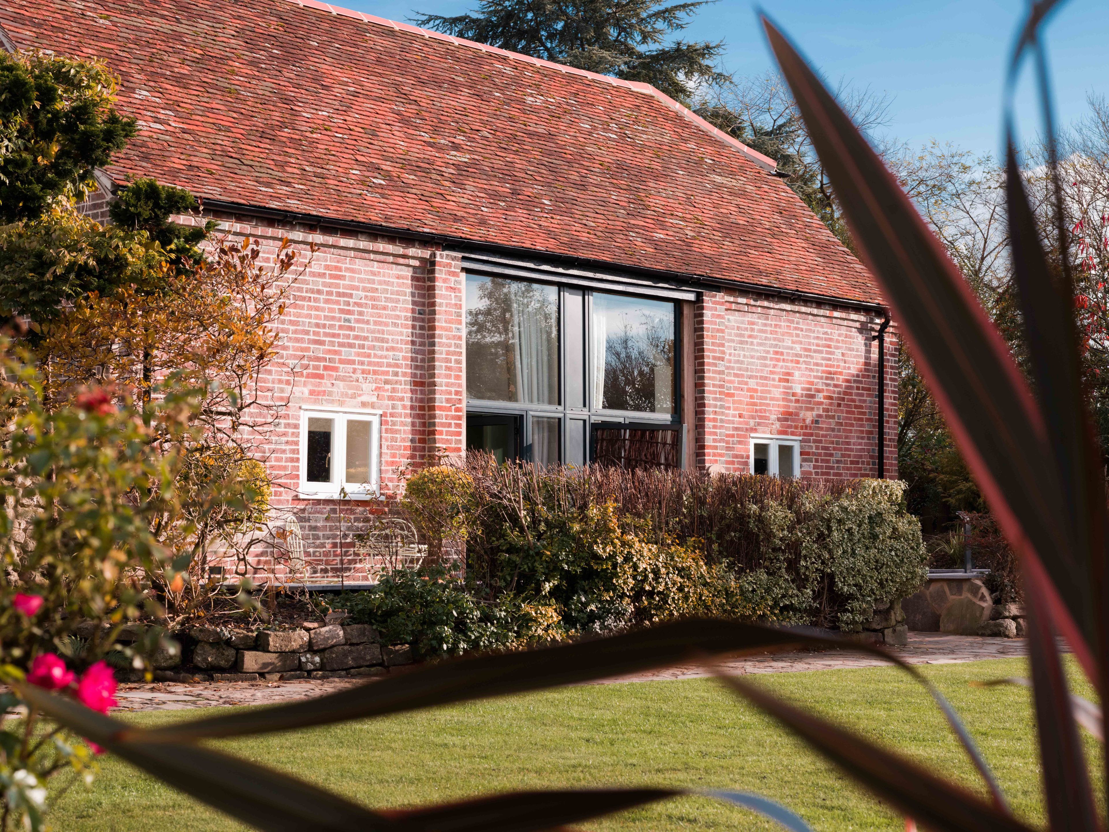 A brick building with large windows, a stone foundation, and a well-maintained garden.