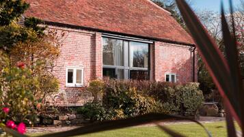 A brick building with large windows, a stone foundation, and a well-maintained garden.