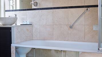 Un baño con un lavamanos grande, un espejo, un espejo de mano, una barra de apoyo y un inodoro.