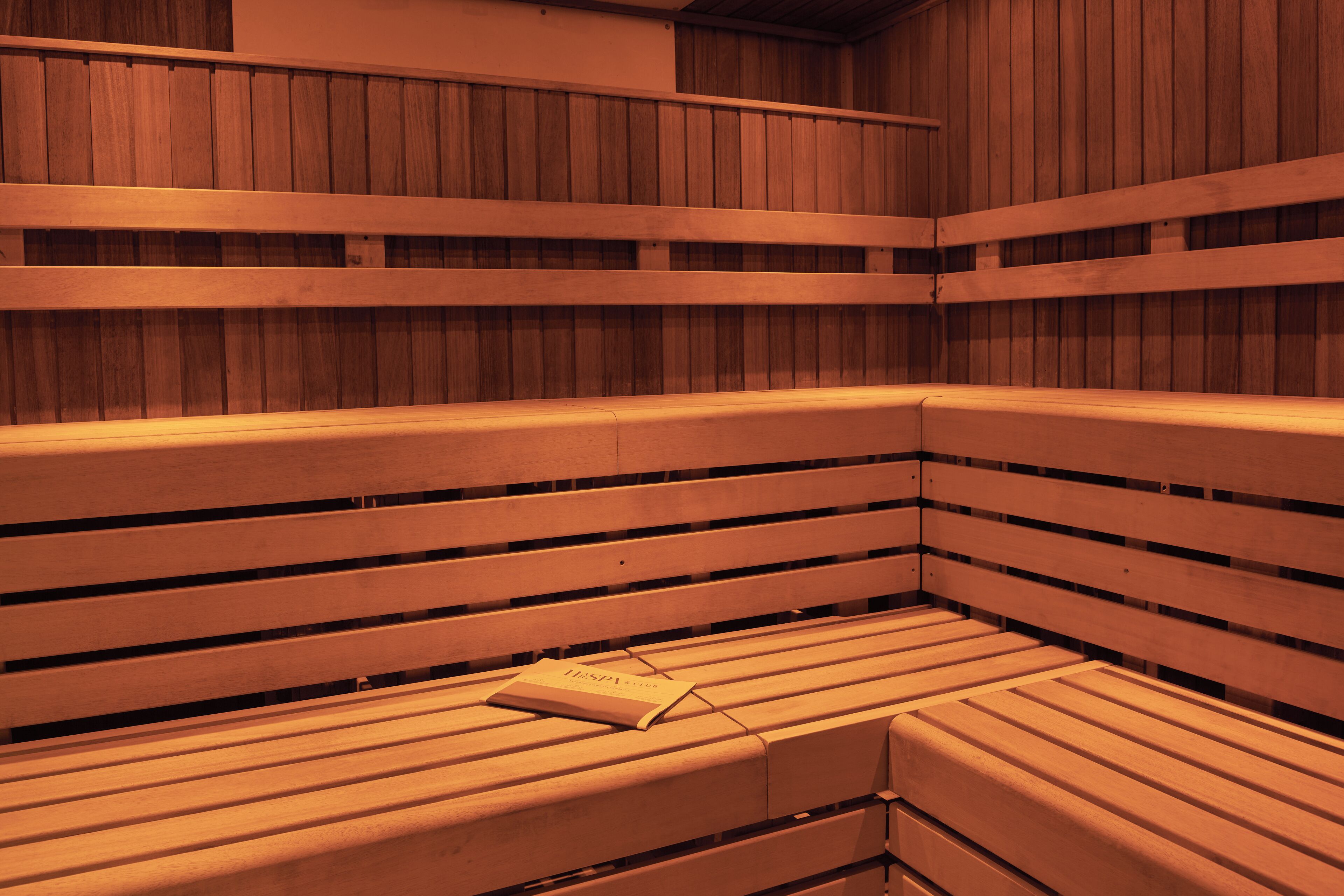 A sauna with wooden benches and a book placed on one of them.