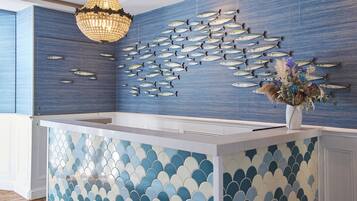 Zona de recepción con una pared decorada con peces y un jarrón ornamental.