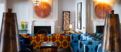 Una sala moderna con chimenea, sofás coloridos con estampado y una mesa de centro de vidrio.
