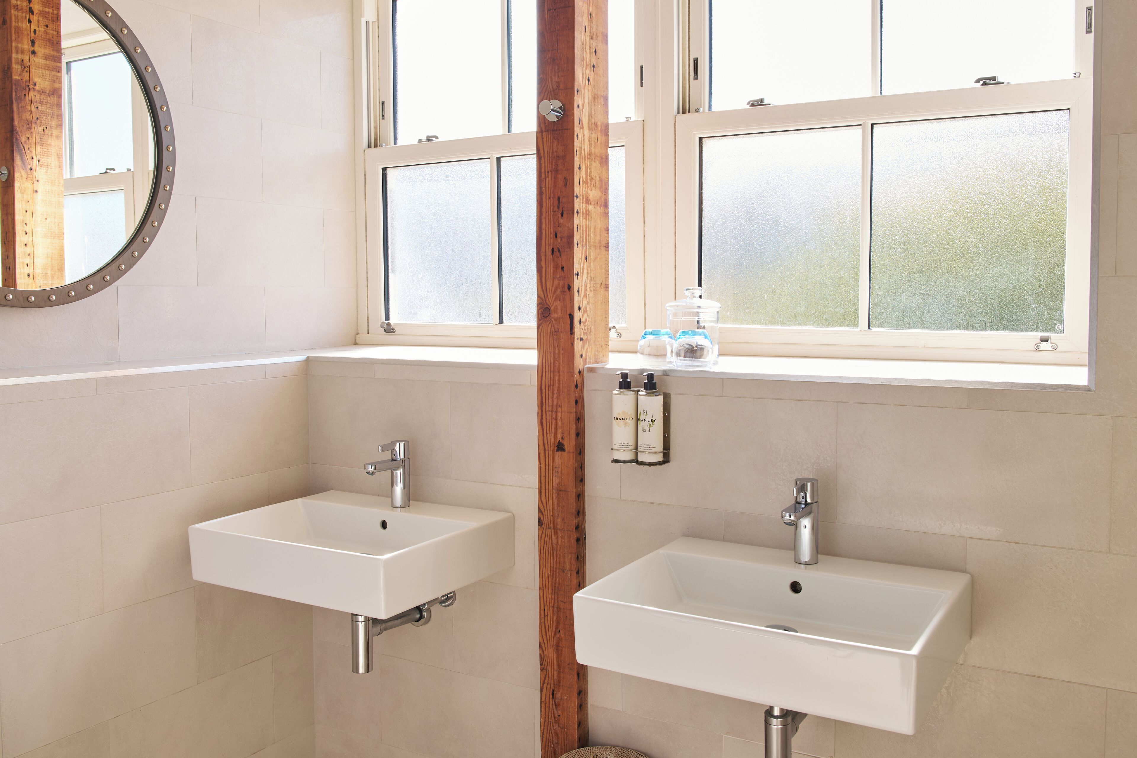 A bathroom with two sinks, wooden beams, and frosted windows.