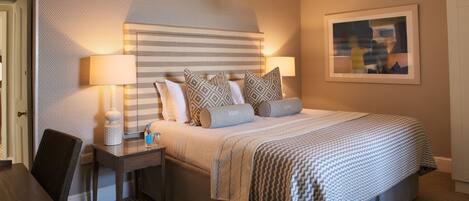 A neatly arranged hotel room with a bed, bedside lamps, a small table, and a chair.