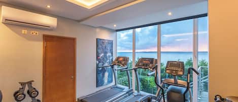 Ein modernes Fitnessstudio mit Laufbändern, Hanteln und einem großen Fenster mit Panoramablick.