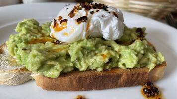Un sándwich con crema de aguacate y un huevo pochado sobre tostada, adornado con hojuelas de chile.