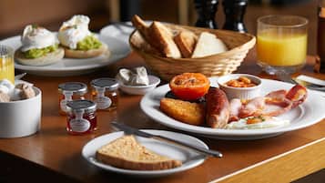 A breakfast table with toast, eggs, bacon, and a glass of orange juice.
