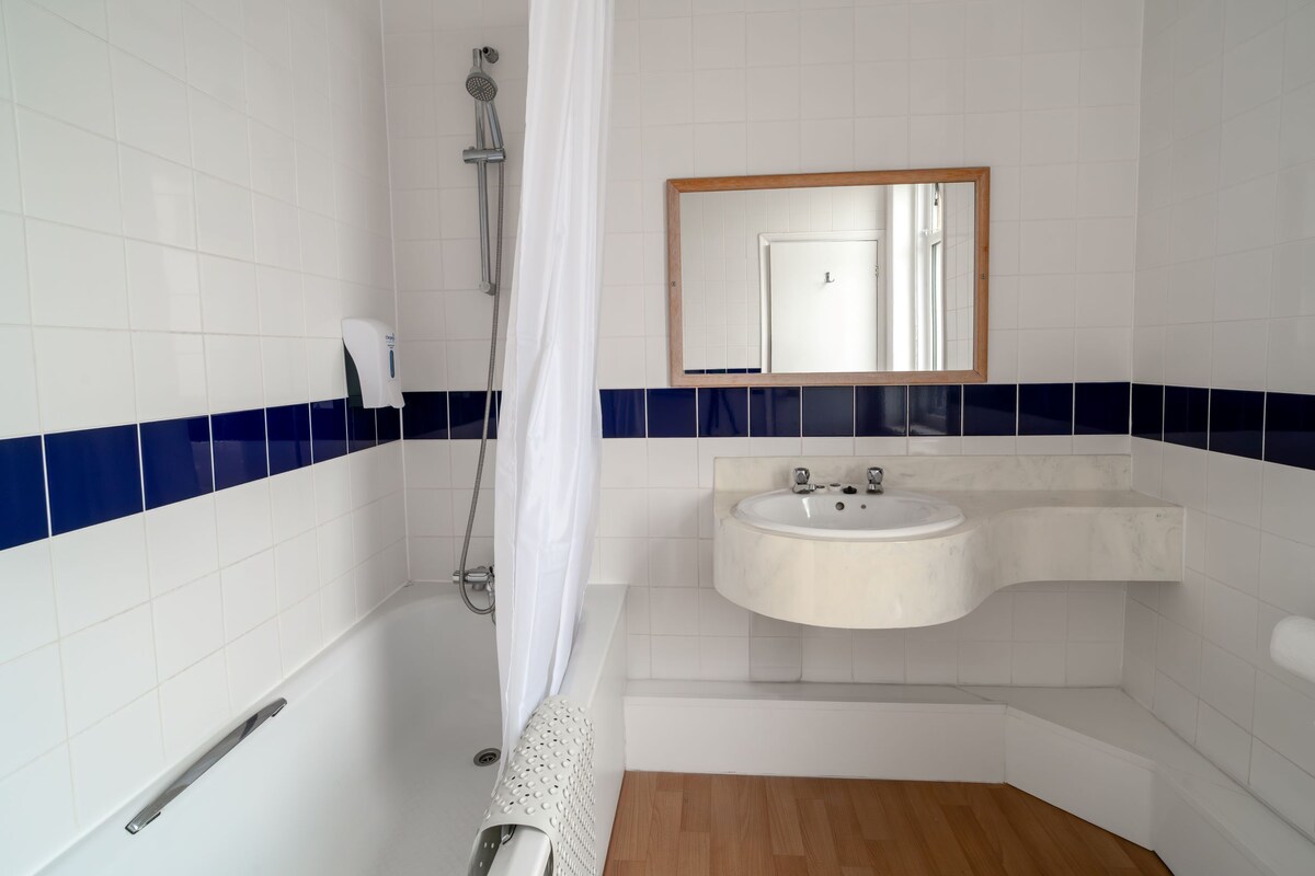 Un baño con bañera, lavamanos, ducha y espejo.