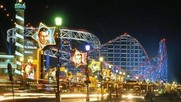 Ein hell erleuchteter Vergnügungspark bei Nacht mit Achterbahnen und leuchtenden Schildern.