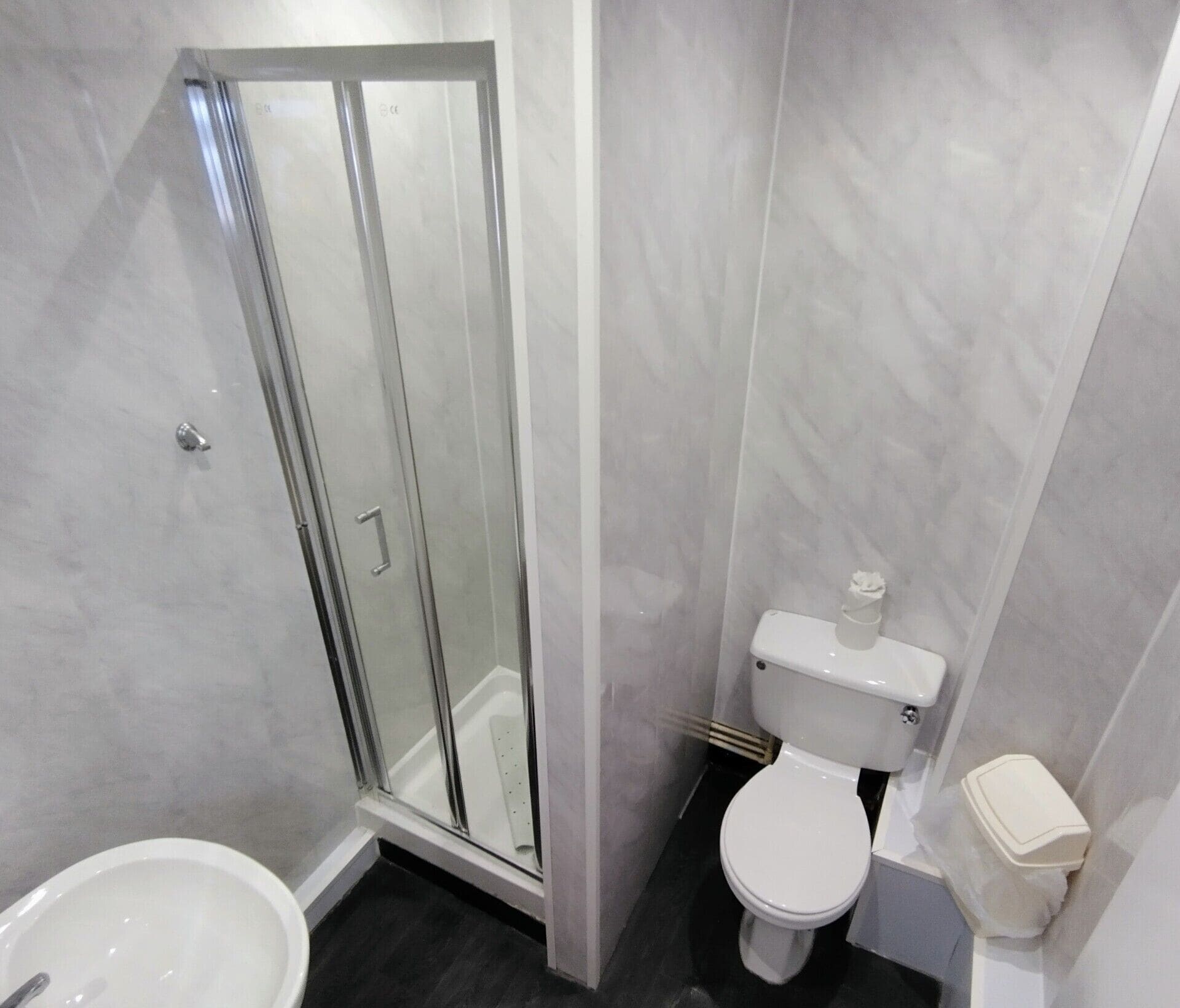 A bathroom with a glass shower enclosure, a toilet, and a bidet.